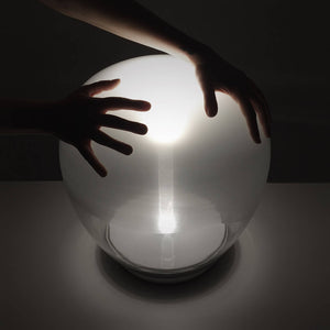 lampada da tavolo Empatia di Artemide con mani sopra il vetro