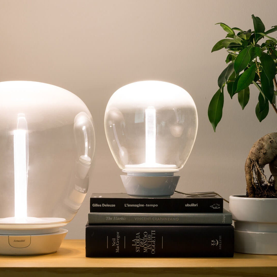 due lampade Empatia di Artemide sopra un comodino con dei libri e una pianta