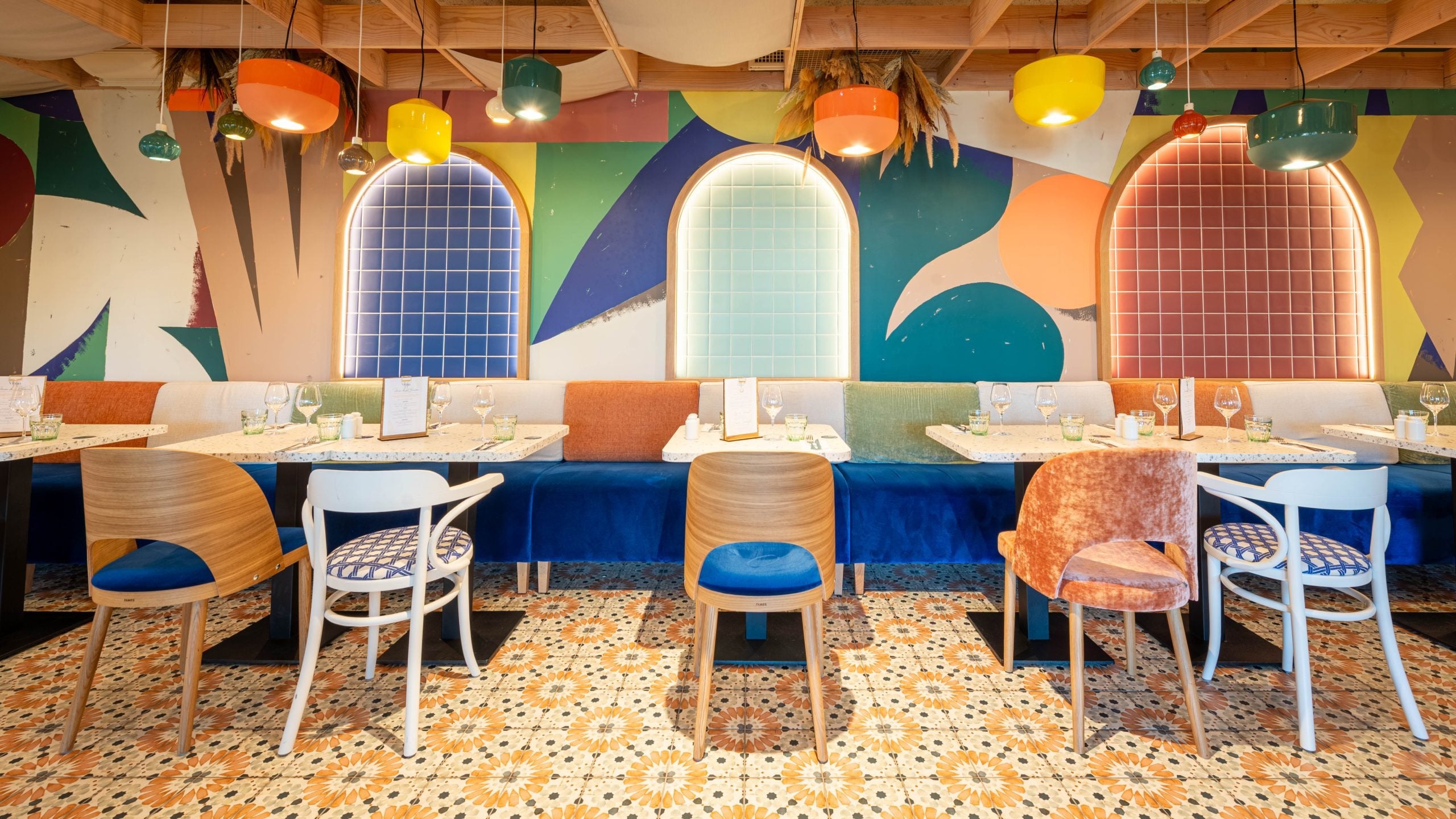 Composizione di lampadari Belotta di Ferroluce in una sala ristorante colorata.